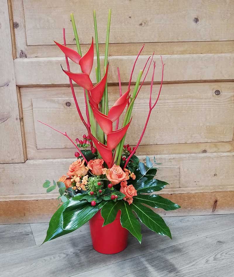 Montage exotique en pot rouge : heliconias, roses orange et feuillages